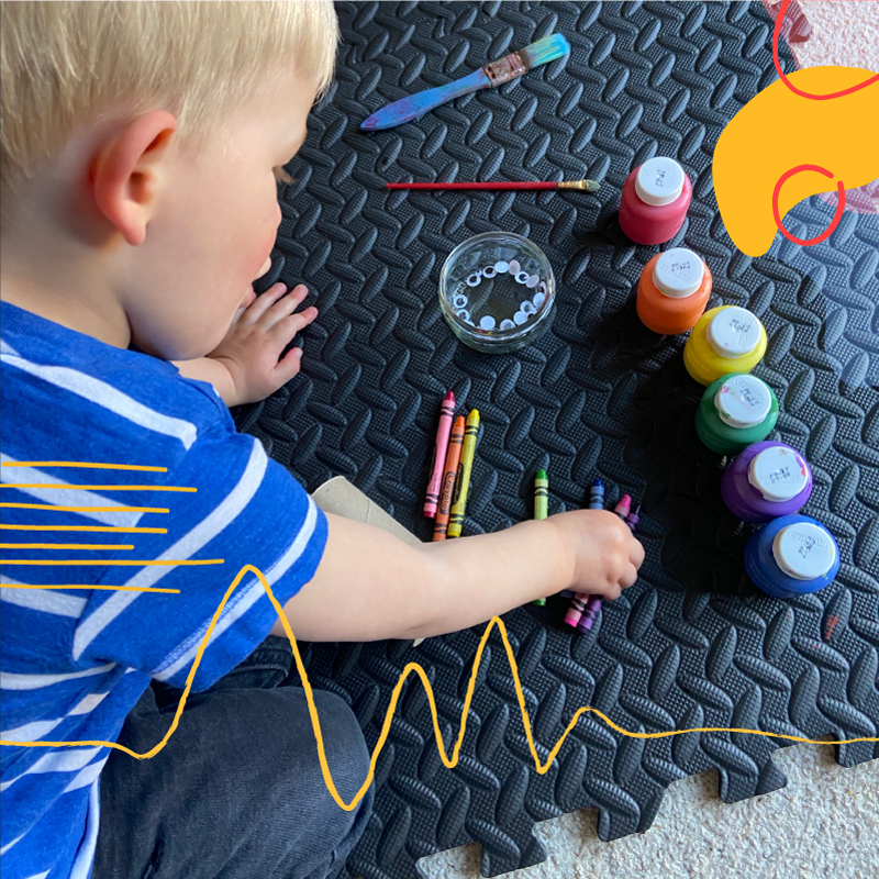 child with paint and paintbrushes ready to create using schoolbox hometime